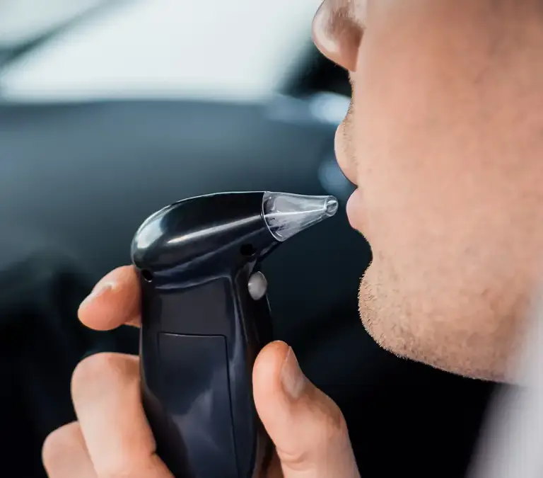 a man using a breathalyzer in a car