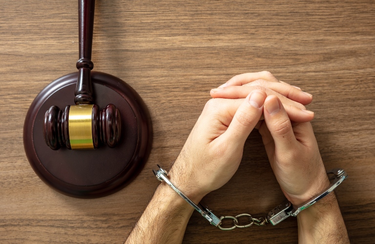 Handcuff locked and judge gavel on a wooden table