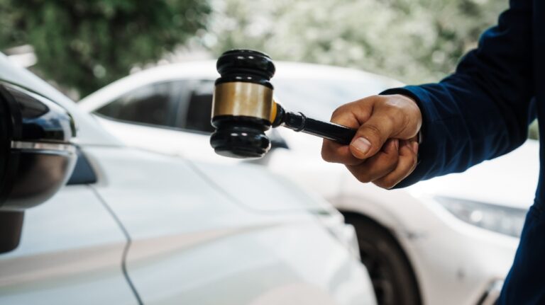 Lawyer is holding gavel in front of car