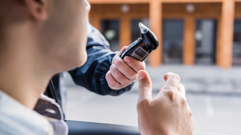 policeman giving breathalyzer to driver in car